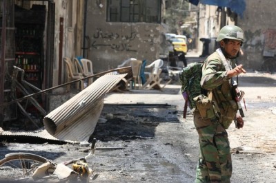 A Syrian soldier gestures in front of damaged buildings during a guided government tour for journalists of the al-Midan area in Damascus on July 20, 2012..jpeg